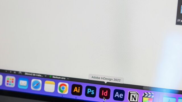 A detailed view of a MacBook Pro displaying Adobe InDesign and other design tools on screen.