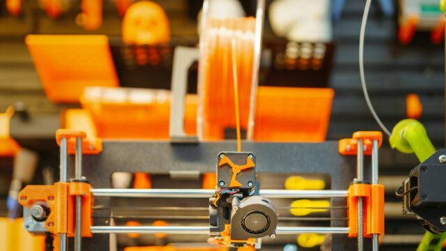 Close-up of an advanced 3D printer extruding filament in a workshop setting.