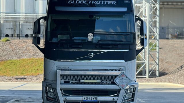 White Globetrotter semi-trailer truck parked outdoors under partial shade.