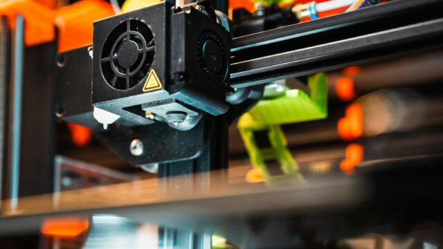 Detailed view of a 3D printer nozzle working in a modern manufacturing setting.