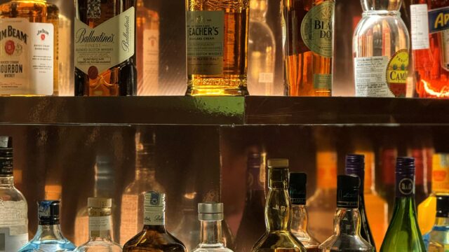 A vibrant display of diverse liquor bottles illuminated on bar shelves, perfect for nightlife themes.