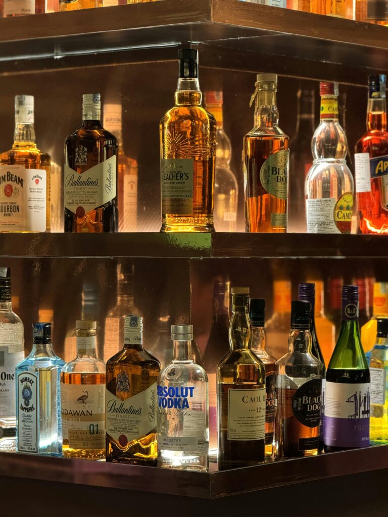 A vibrant display of diverse liquor bottles illuminated on bar shelves, perfect for nightlife themes.