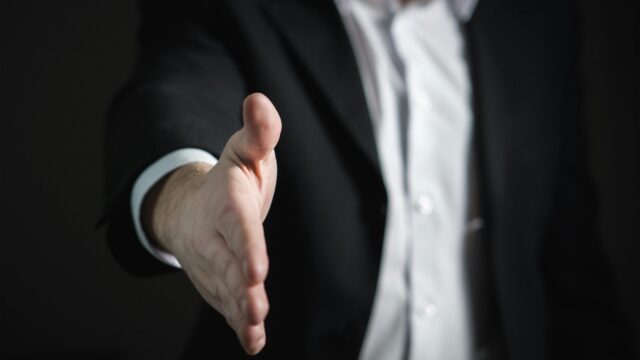 Close-up of a businessman extending hand for a handshake, symbolizing agreement and partnership.