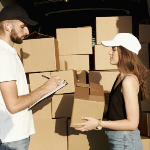 A male and female courier organizing packages in a delivery truck for efficient shipment.