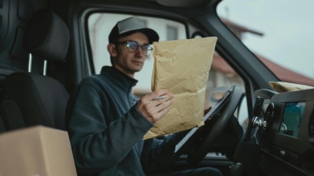 Delivery worker examining packages inside a van, focused on logistics.