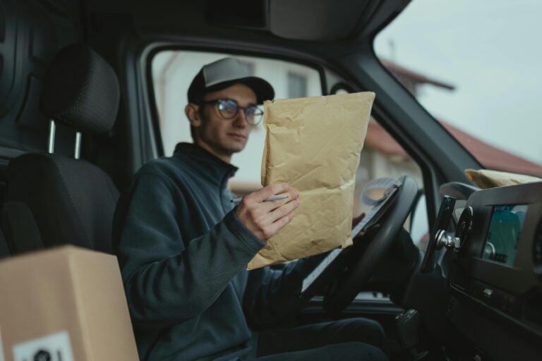 Delivery worker examining packages inside a van, focused on logistics.