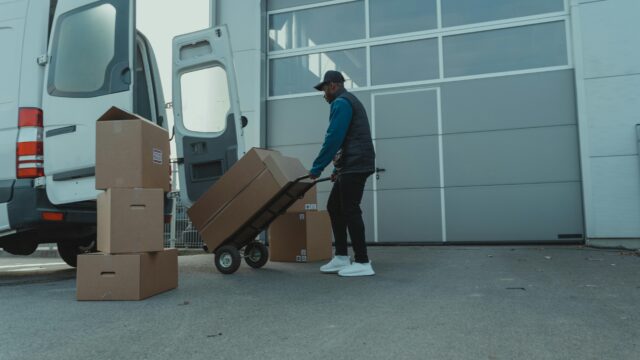 Courier unloading packages from a delivery van at a warehouse entrance. Efficient distribution.