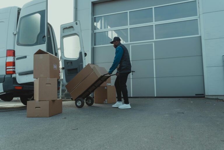 Courier unloading packages from a delivery van at a warehouse entrance. Efficient distribution.