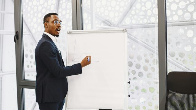Businessman presenting on a flip chart in a contemporary office setting.