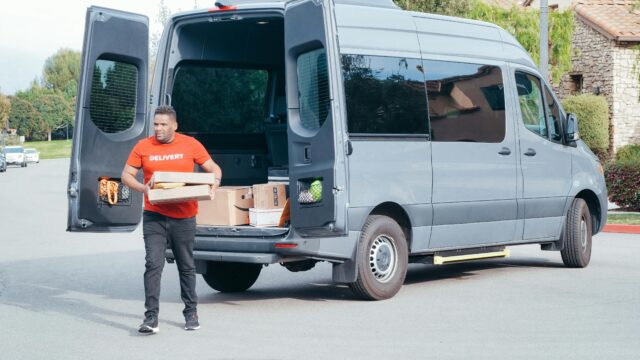 Courier in a delivery van distributing packages in a suburban setting.
