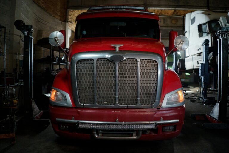 Front view of a red truck parked in a dimly lit industrial garage setting.