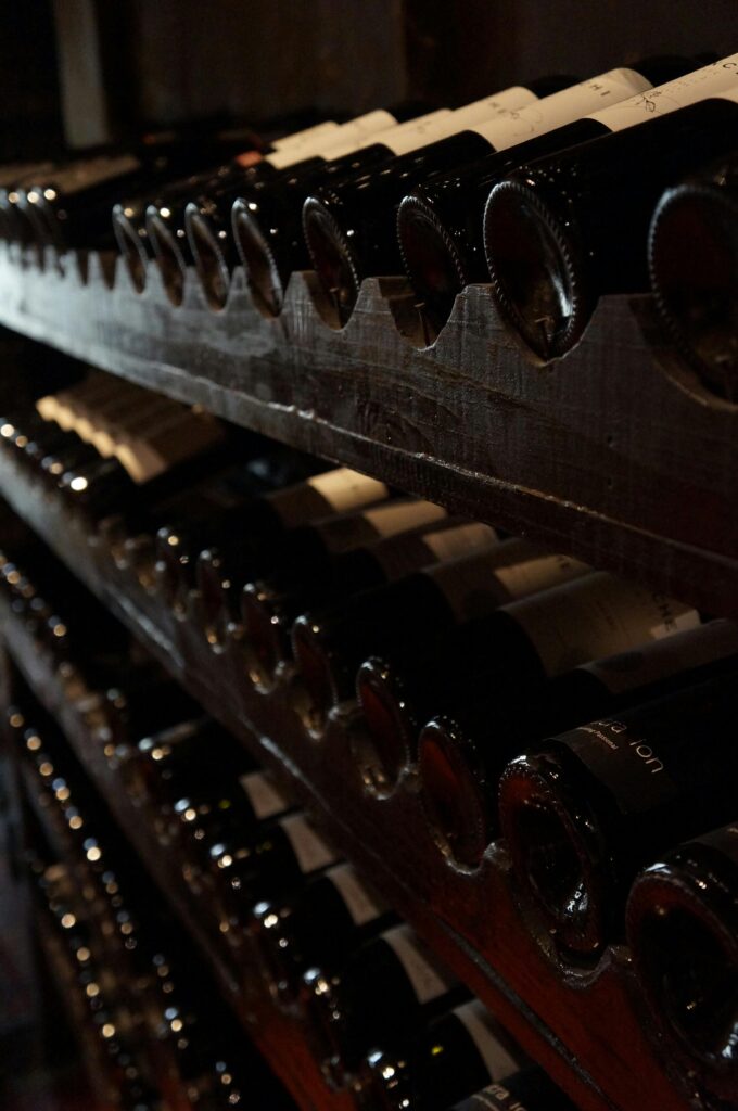 A dimly lit wine cellar showcasing rows of wine bottles on rustic wooden shelves, creating a classic and elegant atmosphere.