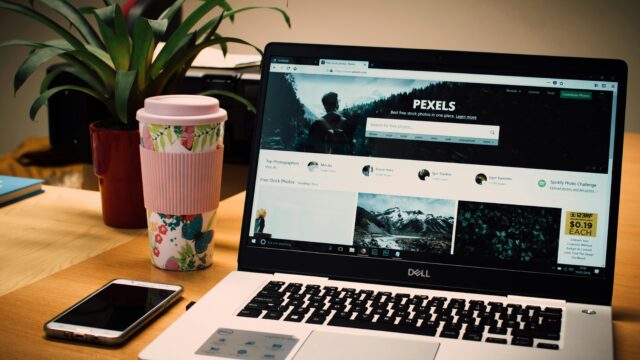 A tidy desk setting with a laptop showing a stock photo website and a smartphone.