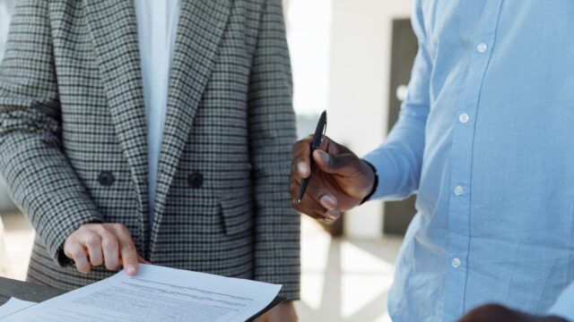Two professionals reviewing business documents and discussing details in an office setting.