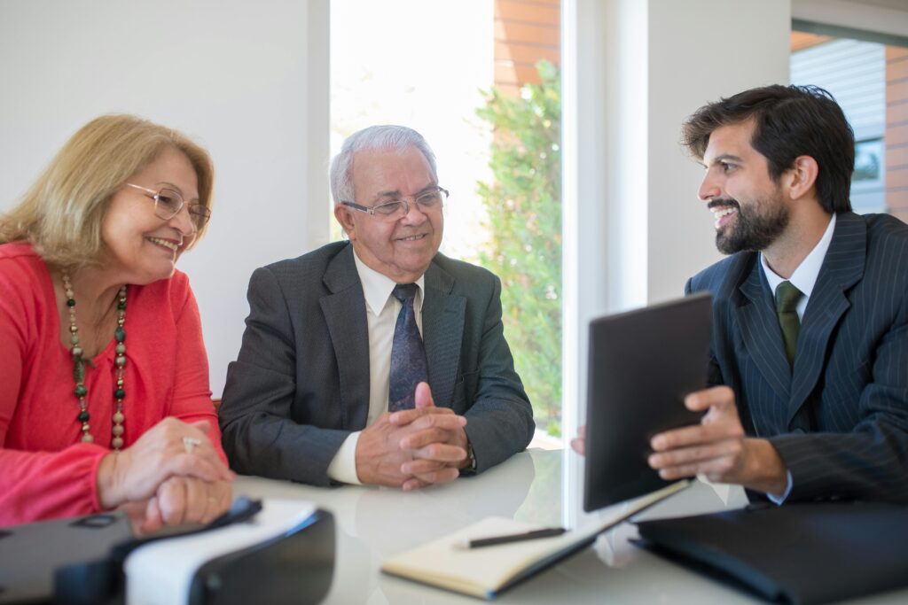 Elderly couple discussing real estate options with an agent in a modern office setting.