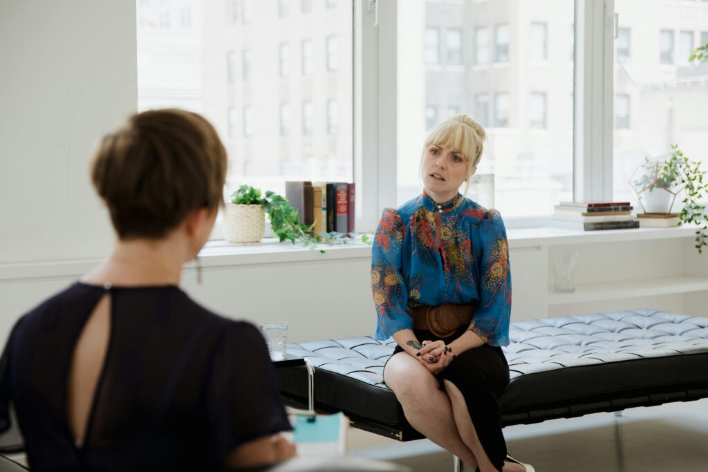 A woman engages in a therapy session with her counselor in a bright, modern office.