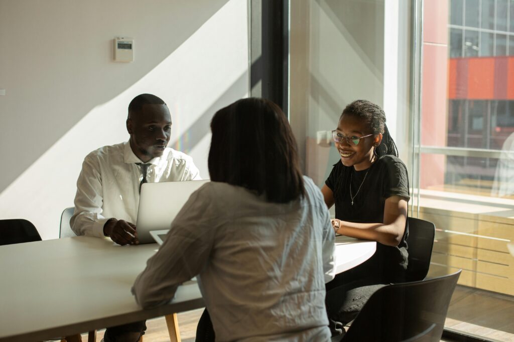 Three professionals engaged in a productive meeting in a sunlit office space.