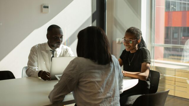 Three professionals engaged in a productive meeting in a sunlit office space.